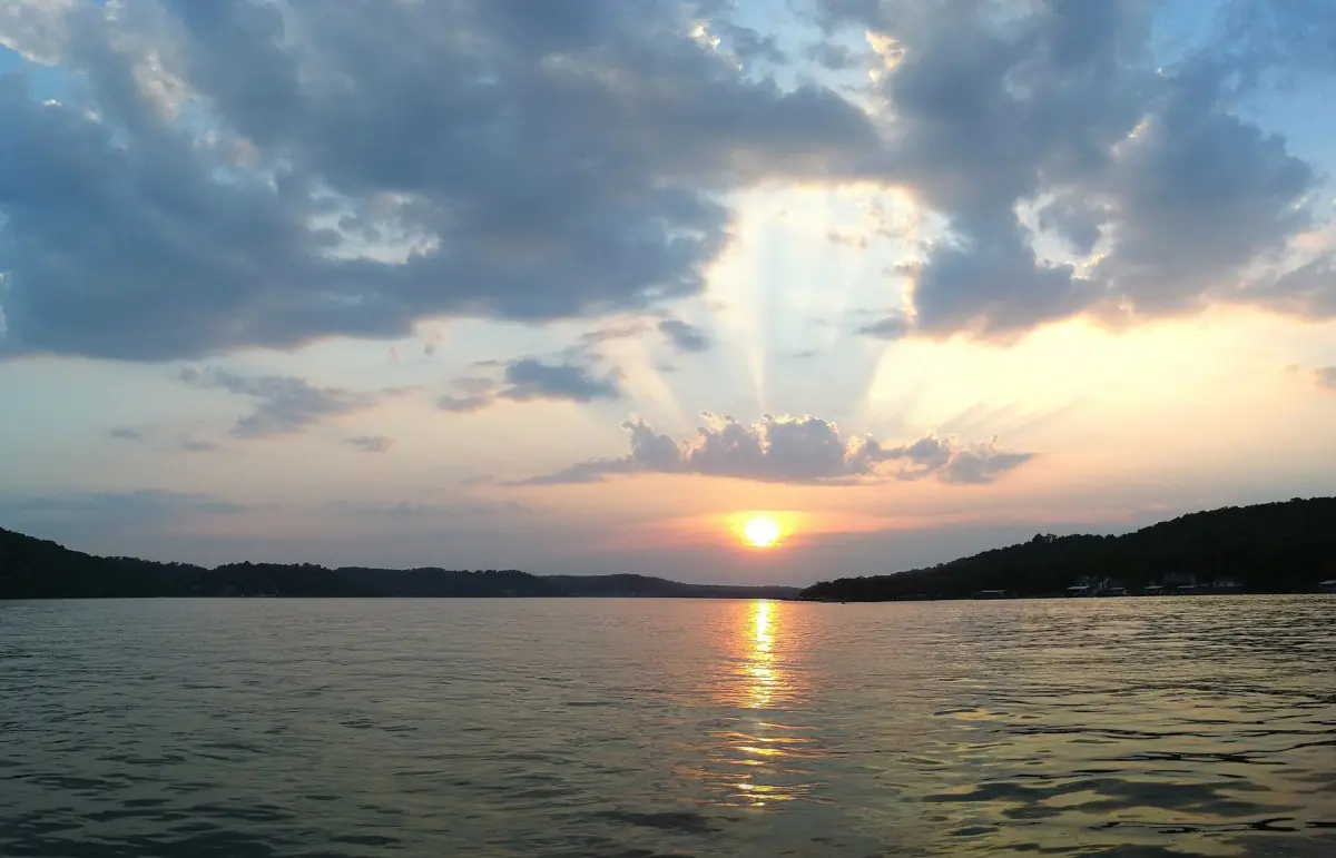 Sun rays breaking through clouds over the calm water of Lake of the Ozarks