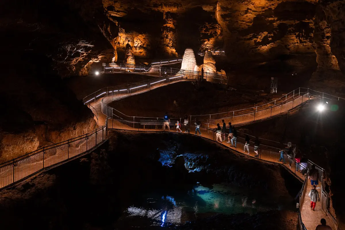 Lit walkway winding above dark water between rock walls in Onondaga Cave